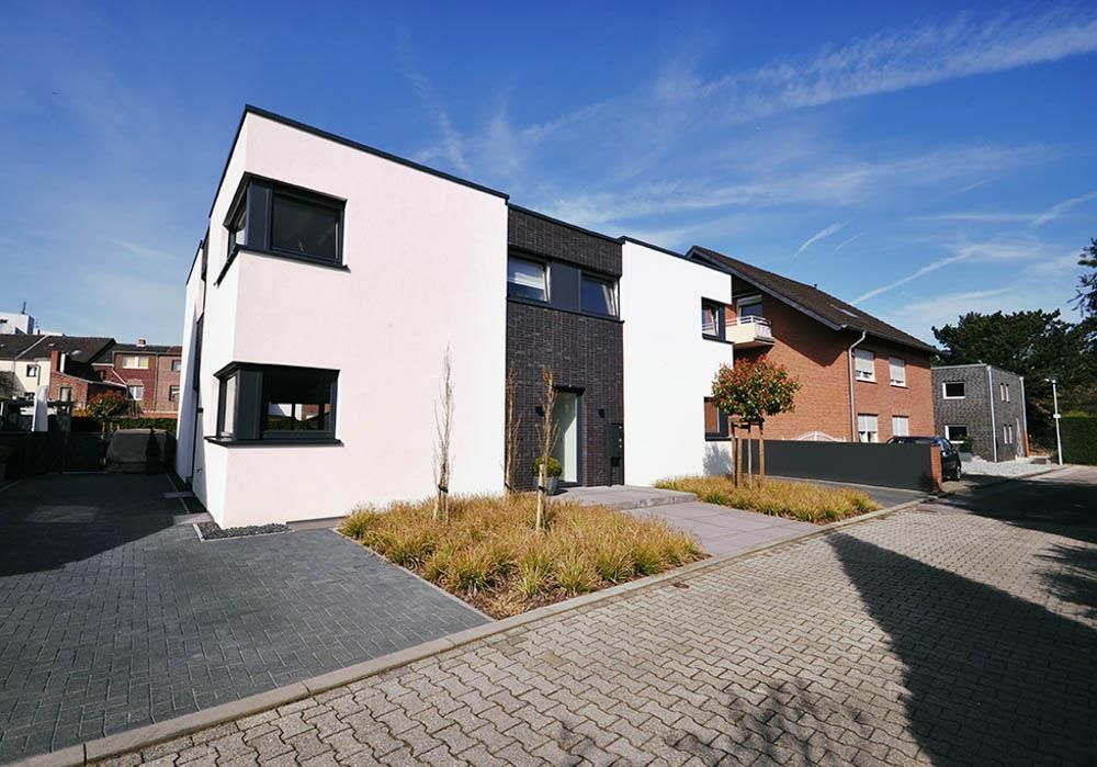 Ein rosa-weißes Gebäude mit einer gepflasterten Auffahrt davor