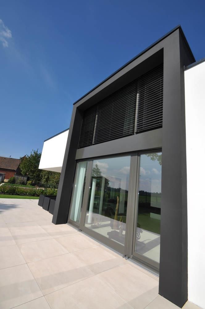 Ein schwarz-weißes Gebäude mit einer Terrasse davor