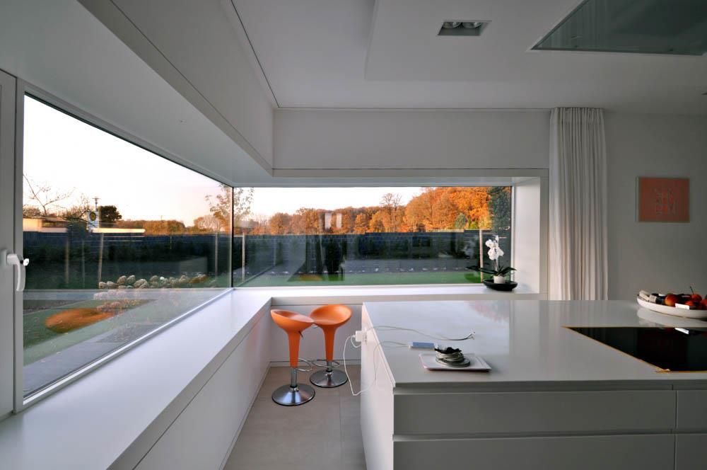 Eine Küche mit zwei orangefarbenen Barhockern und einem großen Fenster