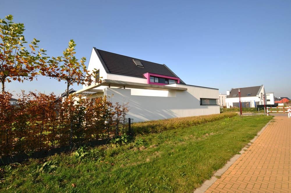 Ein weißes Haus mit einem rosa Dach steht neben einem Ziegelweg