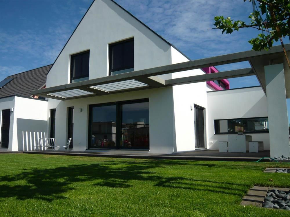 Ein weißes Haus mit einem rosa Dach steht auf einem üppigen grünen Rasen