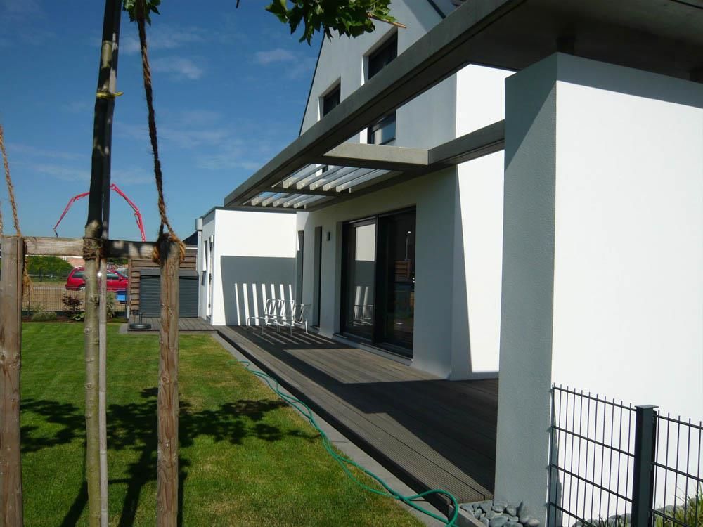 Ein Haus mit einer Pergola und einem Schlauch davor