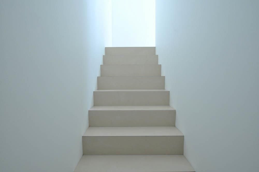 Eine Treppe führt hinauf zu einem Licht in einem weißen Raum.