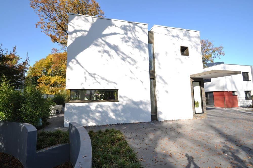 Ein weißes Gebäude mit einer roten Garage ist von Bäumen umgeben