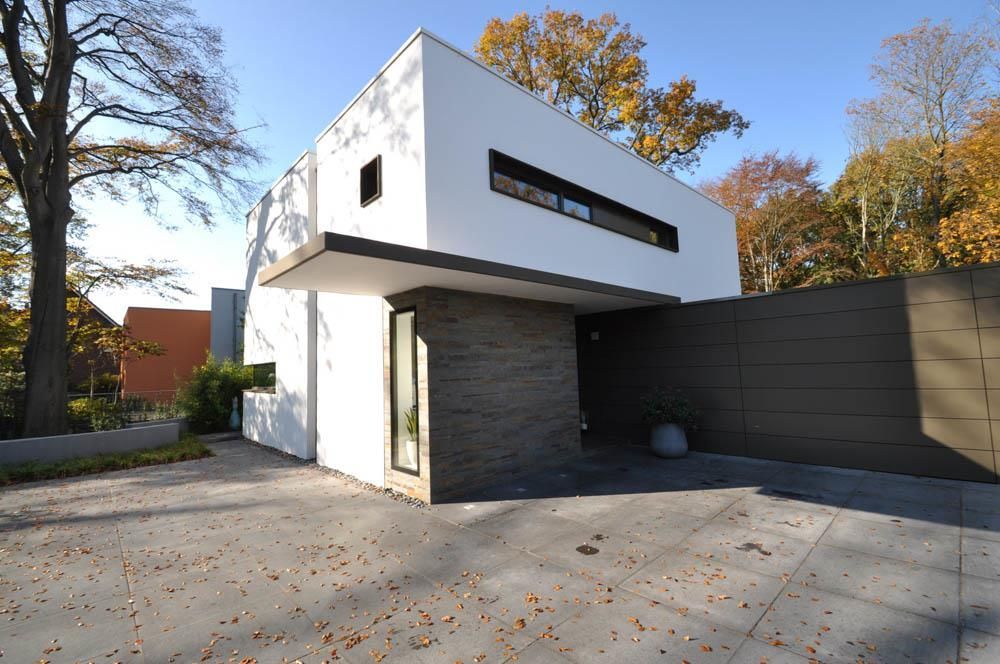 Ein weißes Haus mit einer Backsteinmauer und einer Betonauffahrt