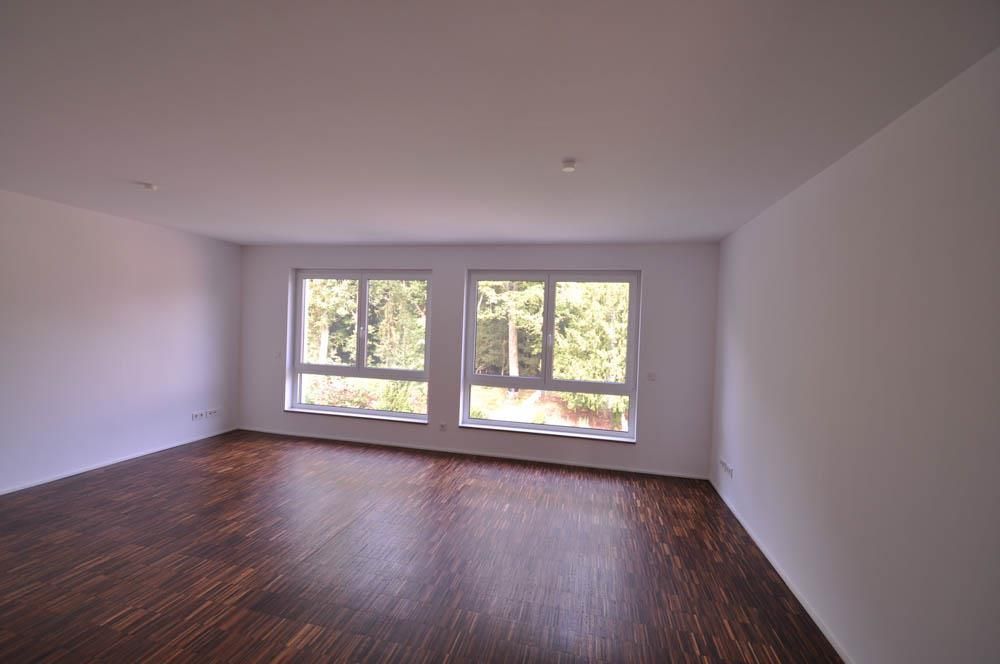 Ein leerer Raum mit Holzboden und zwei Fenstern