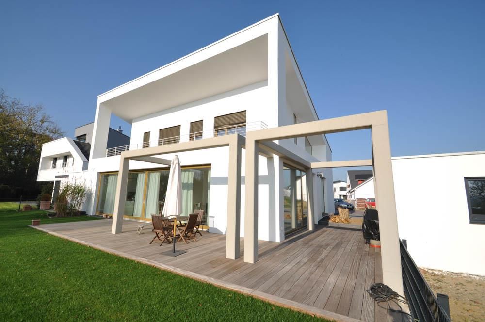 Ein großes weißes Haus mit einer Holzterrasse davor