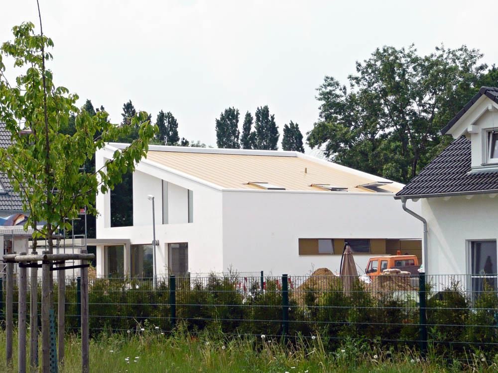 Ein weißes Haus mit einem gelben Dach ist von Bäumen umgeben