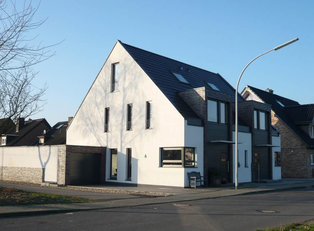 Ein weißes Haus mit schwarzem Dach steht an der Ecke einer Straße