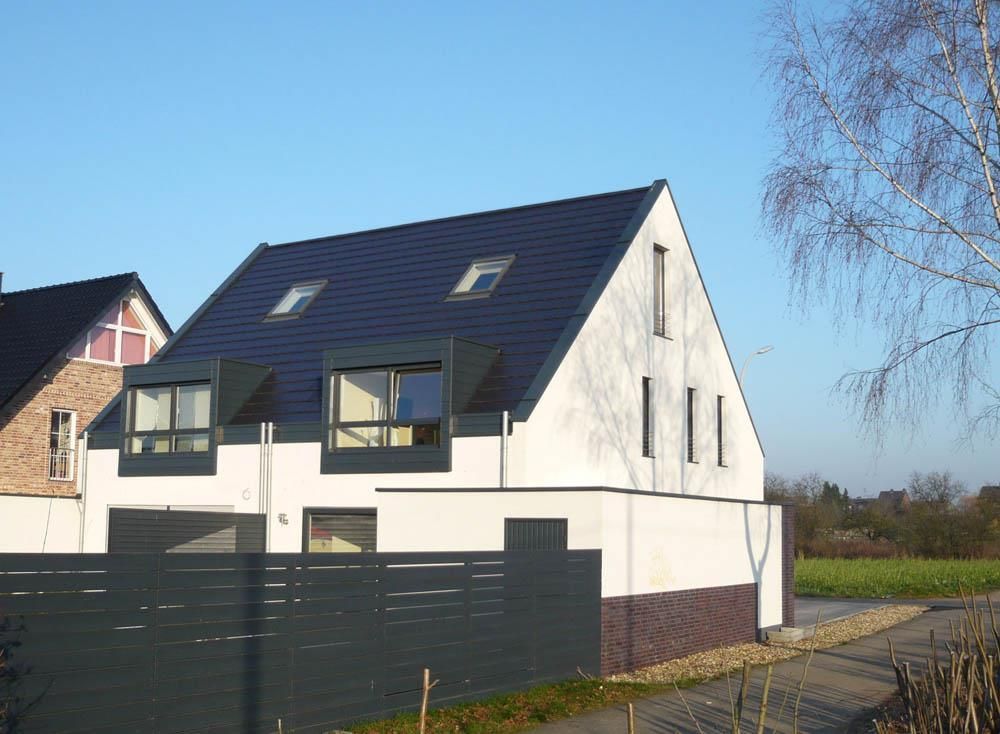 Ein weißes Haus mit einem schwarzen Zaun davor