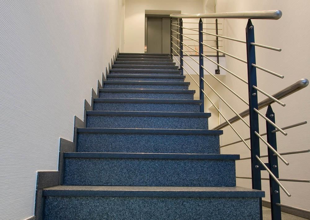 Eine Reihe von blauen Treppen mit einem Geländer aus Edelstahl