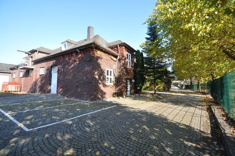 Eine gepflasterte Auffahrt führt zu einem großen Backsteingebäude