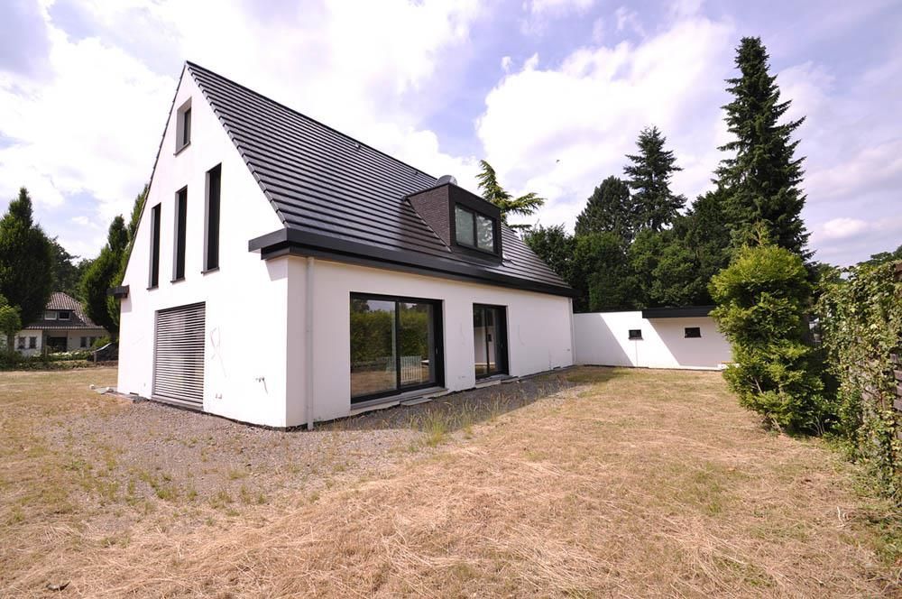 Ein weißes Haus mit schwarzem Dach und vielen Fenstern