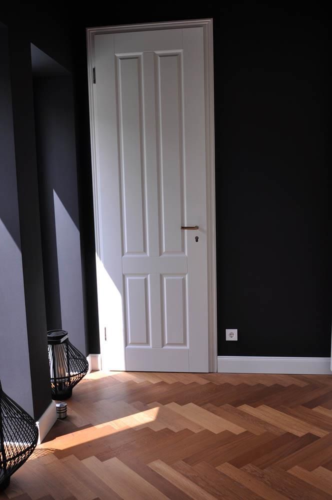 Ein Flur mit Fischgrätboden und weißer Tür