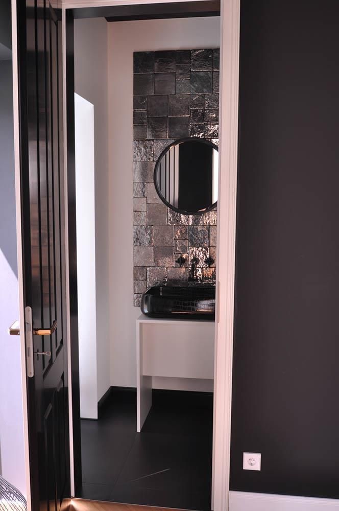 Ein Badezimmer mit einem schwarzen Waschbecken und einem runden Spiegel