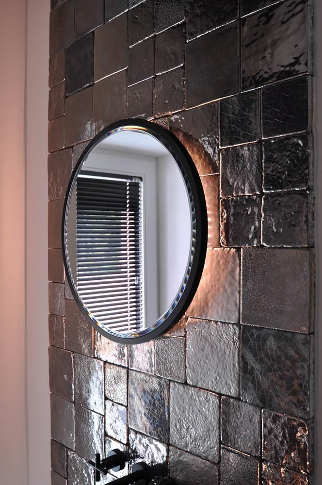 Ein Badezimmer mit einem runden Spiegel an der Wand