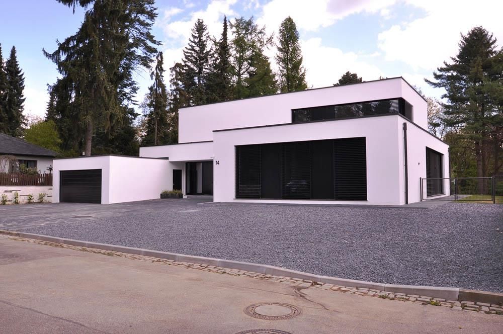 Ein weißes Haus mit einem schwarzen Garagentor ist von Bäumen umgeben