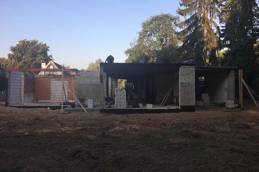 Auf einem Feld mit Bäumen im Hintergrund wird ein Haus gebaut
