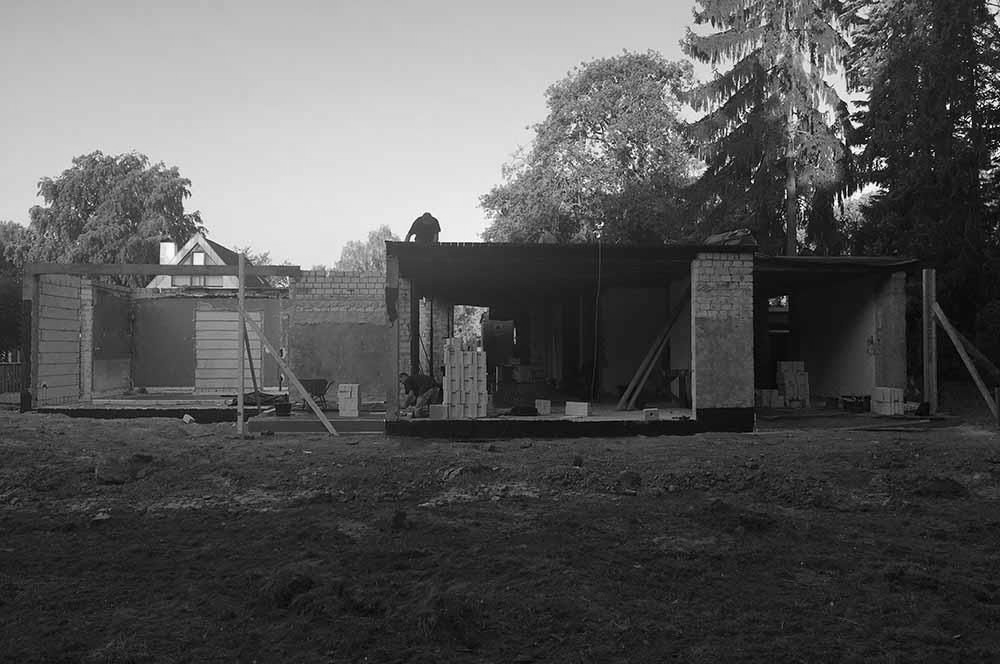 Auf einem Feld mit Bäumen im Hintergrund wird ein Haus gebaut