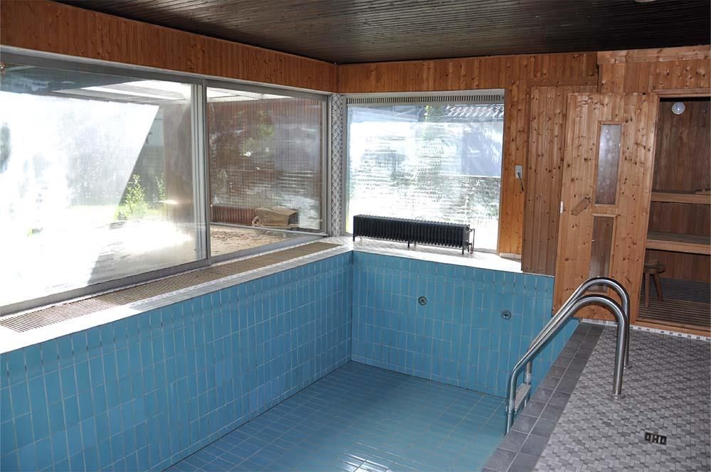 Ein Hallenbad mit blauen Fliesen und einer Holzsauna