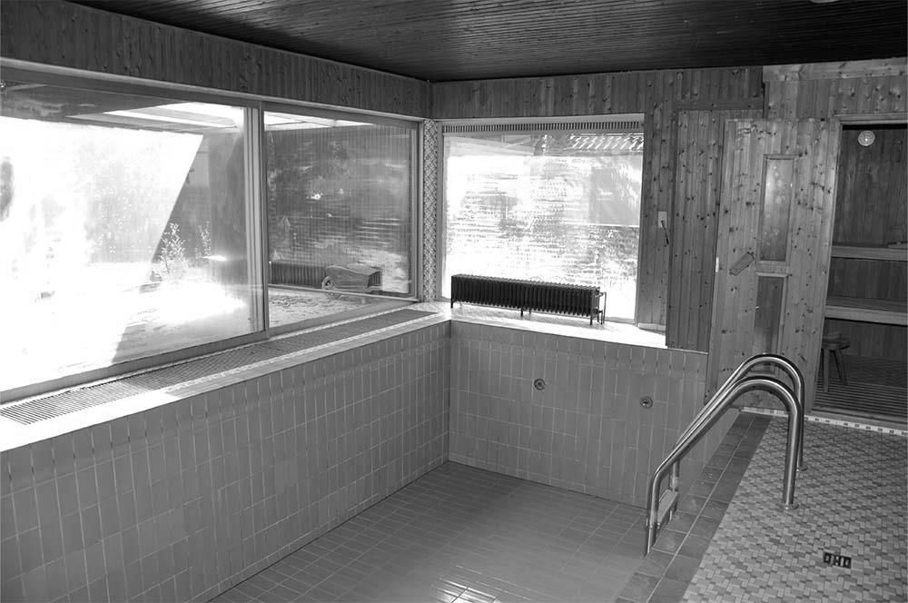 Ein Hallenbad mit blauen Fliesen und einer Holzsauna