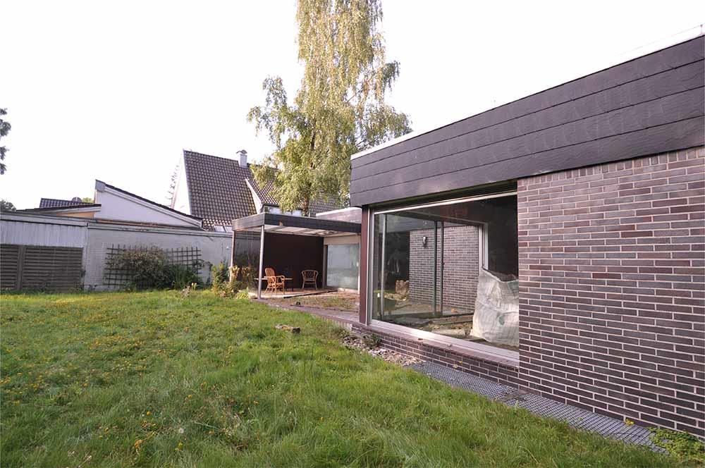 Ein Backsteinhaus mit einem großen Fenster und einem Rasen davor