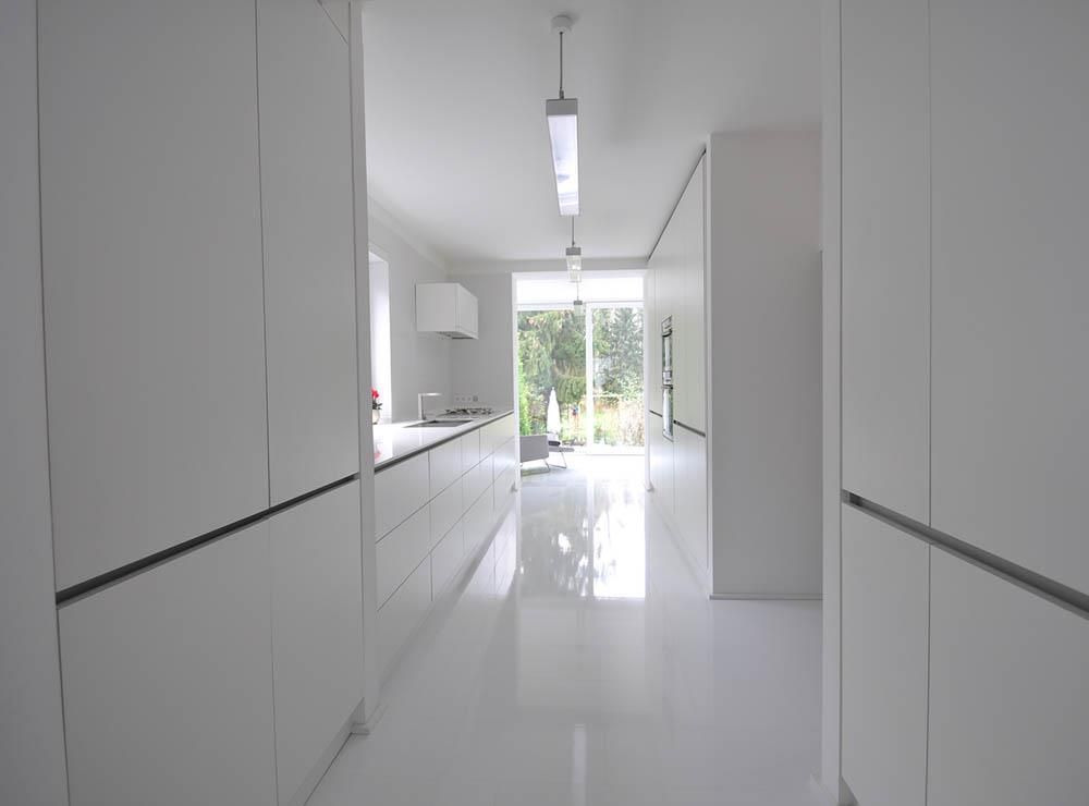 Eine Küche mit weißen Schränken und einer Glasschiebetür