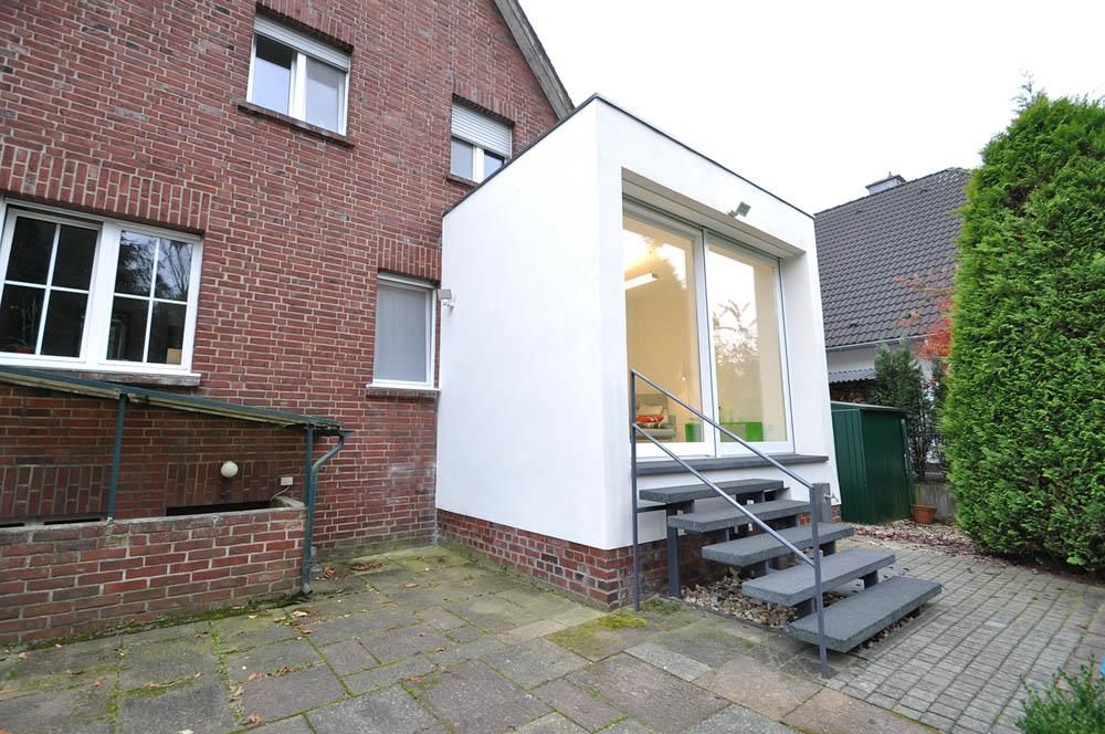 Ein weißes Gebäude mit Treppen, die hinaufführen, steht neben einem Backsteingebäude