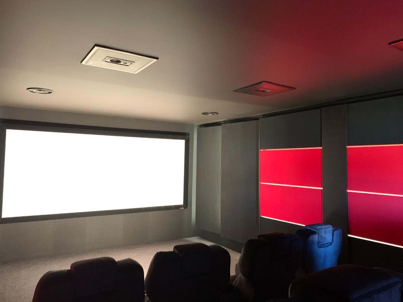 Une pièce avec un écran de projection et un mur rouge.