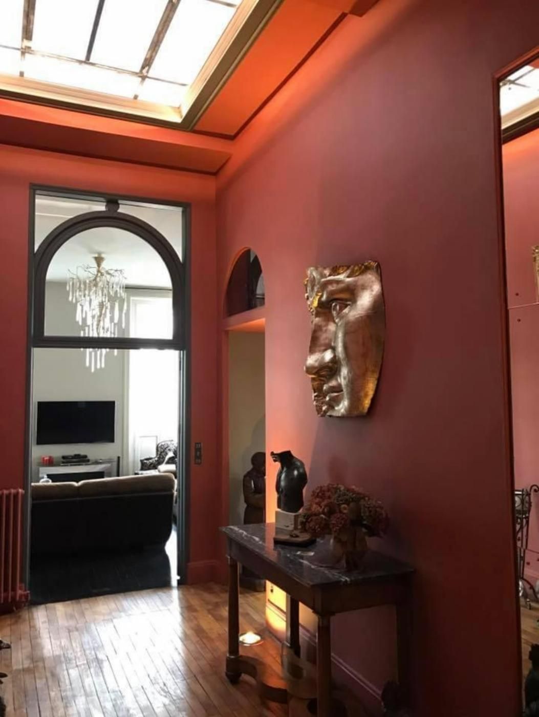 Une pièce avec un parquet en bois et un mur rose.