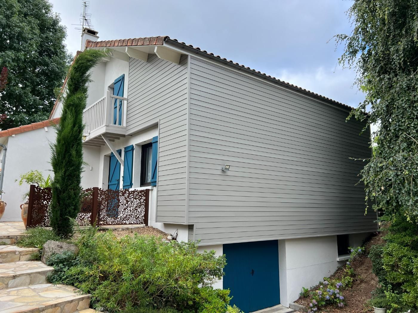Une maison avec une porte bleue et des escaliers qui y mènent.