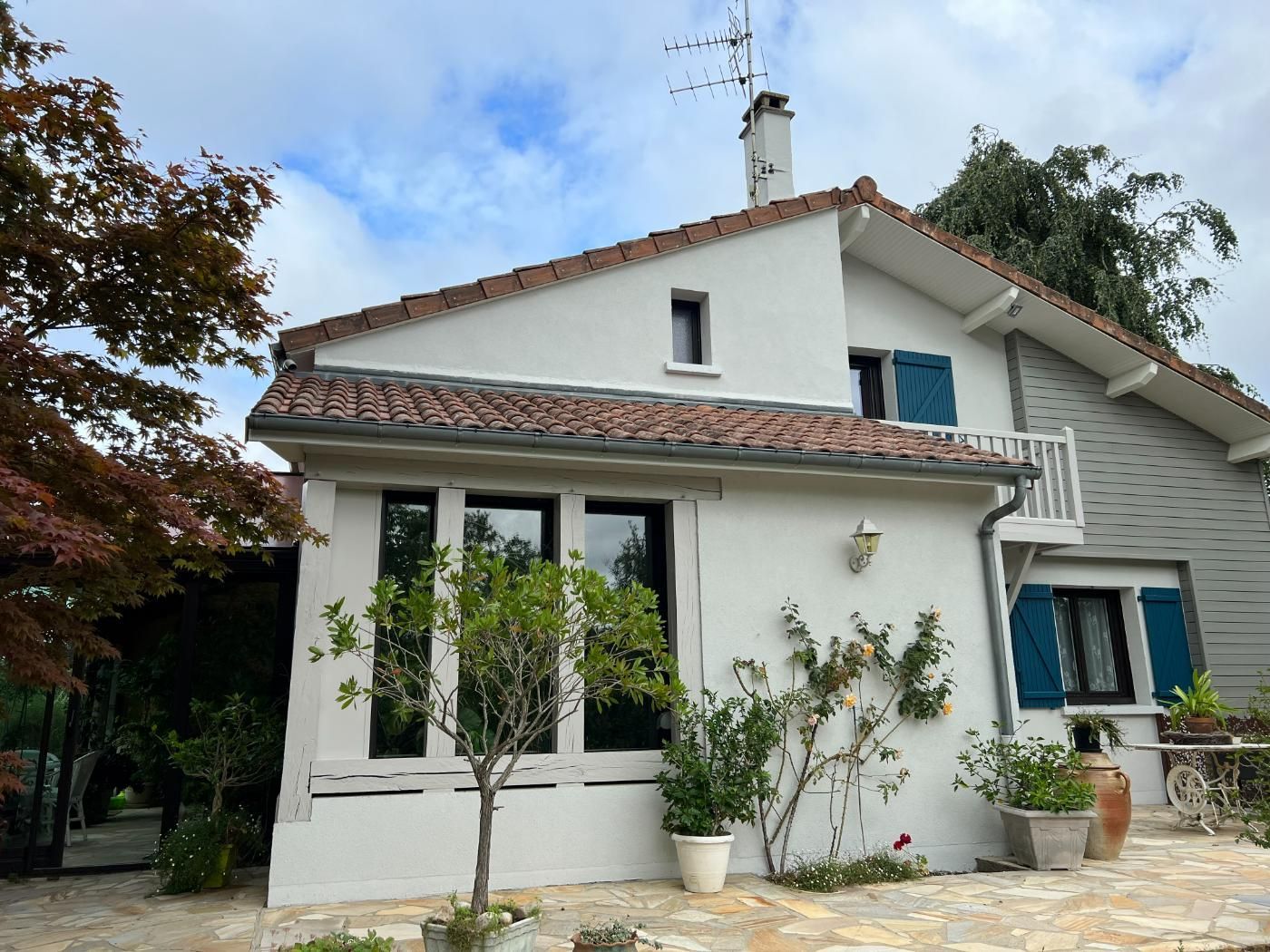 Une maison avec un toit de tuiles et un patio carrelé.