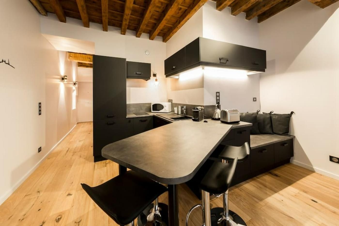 Une cuisine avec des armoires noires et un plafond en bois.