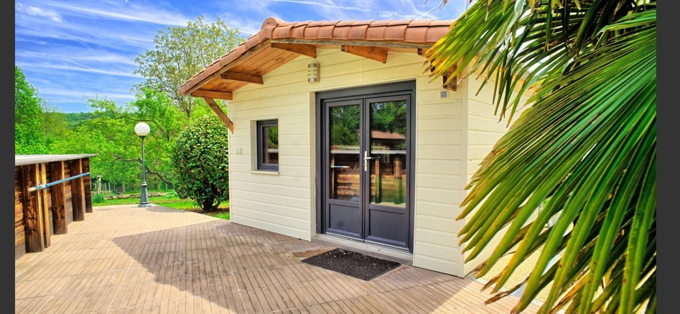 Une petite maison avec une terrasse en bois et une porte.