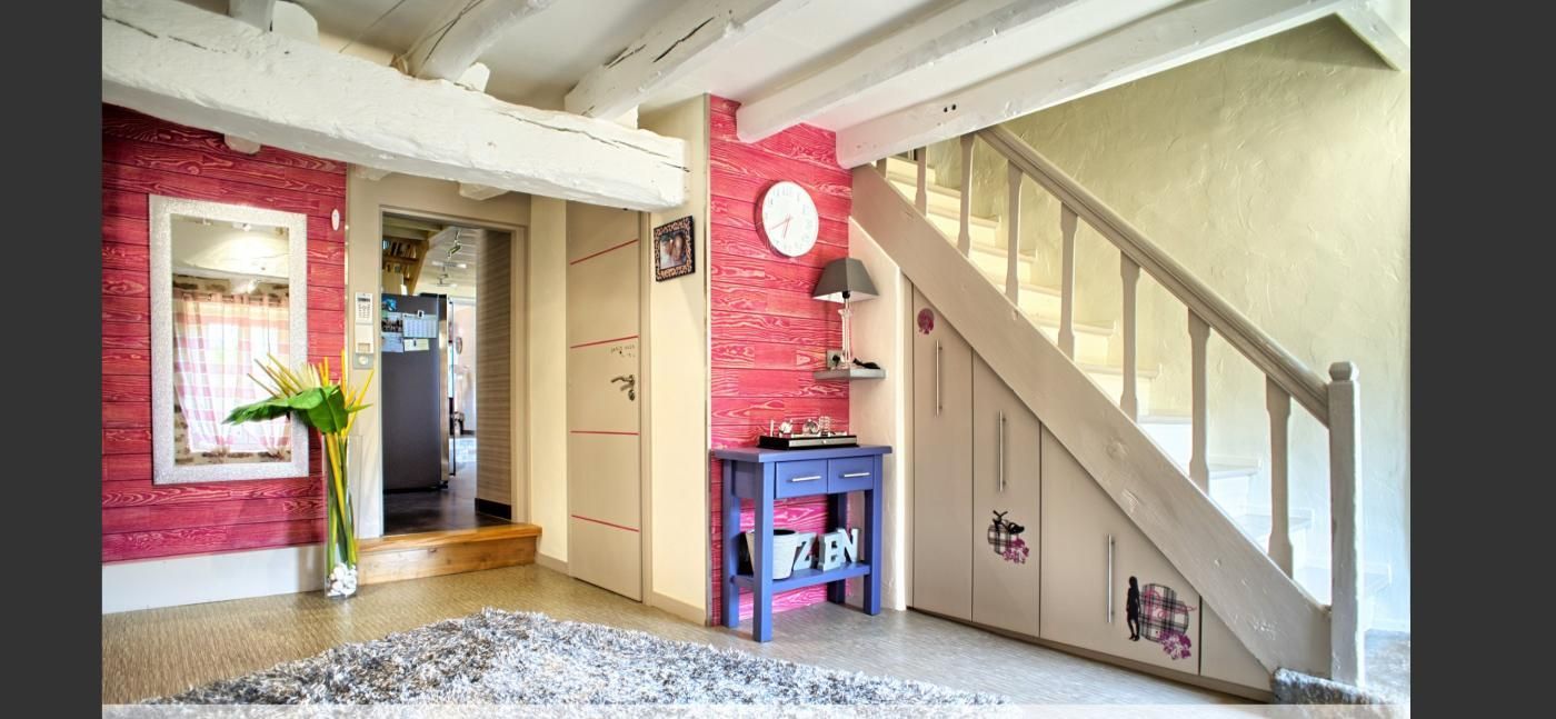 Une pièce avec un escalier et un mur rose.