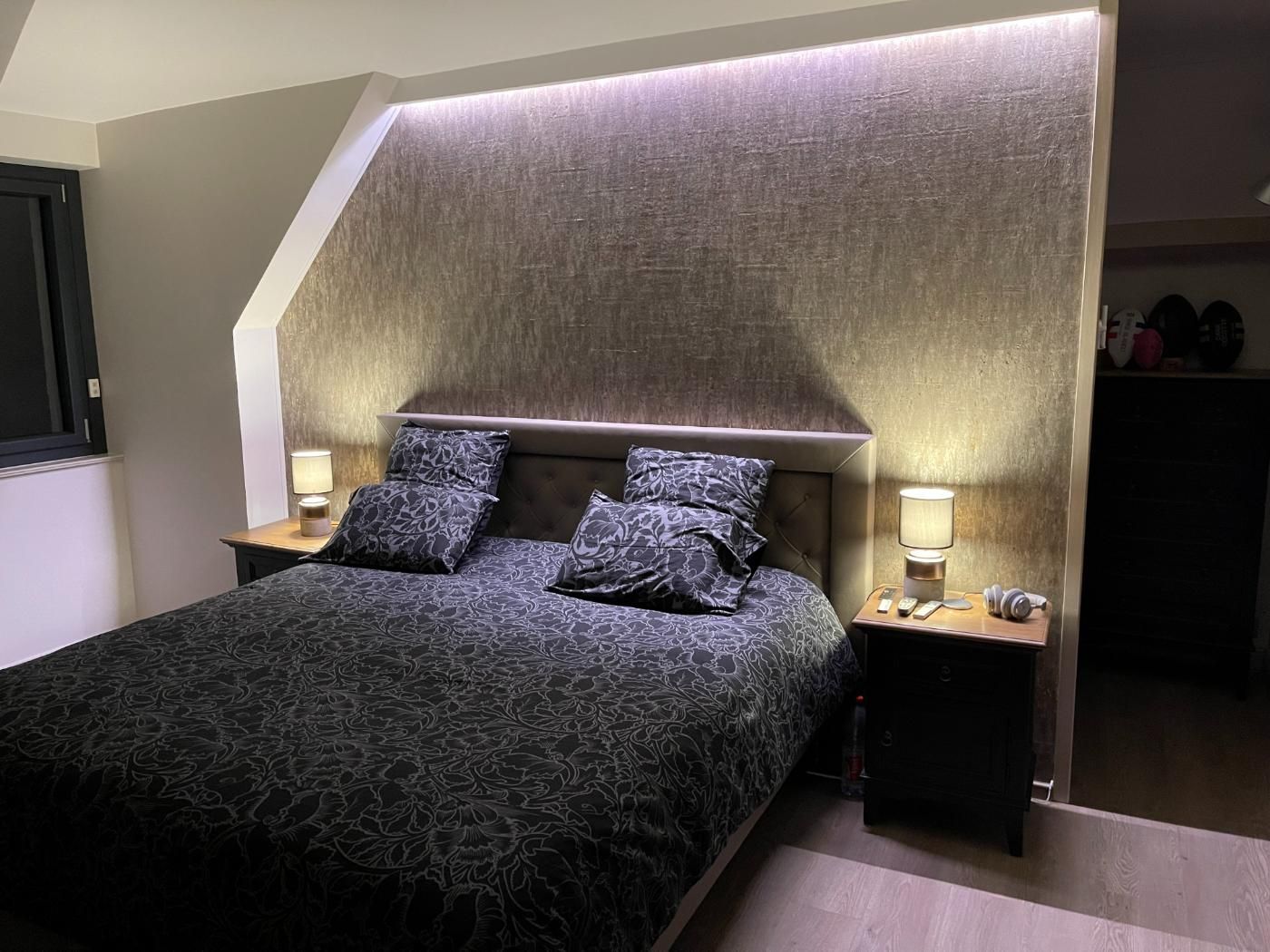 Un lit avec une couette noire et une table de nuit.