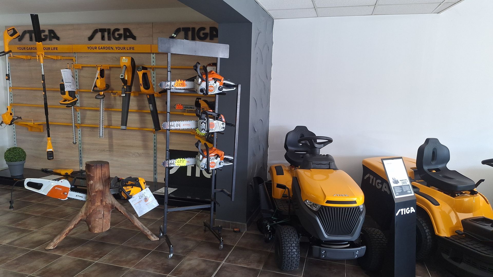 Outils Stiga exposés, notamment des tronçonneuses, des tondeuses autoportées et des équipements électriques d'extérieur.