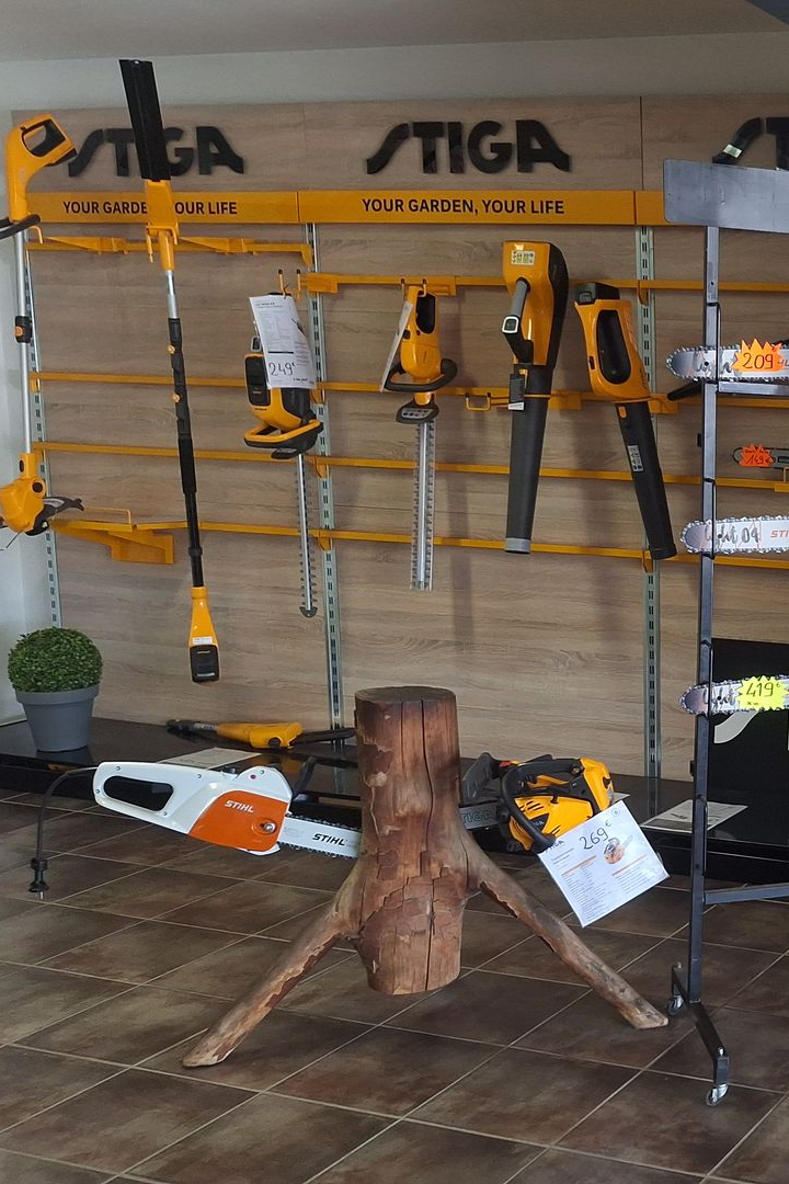 Des tronçonneuses et d’autres outils de jardinage sont exposés sur une étagère dans une quincaillerie.