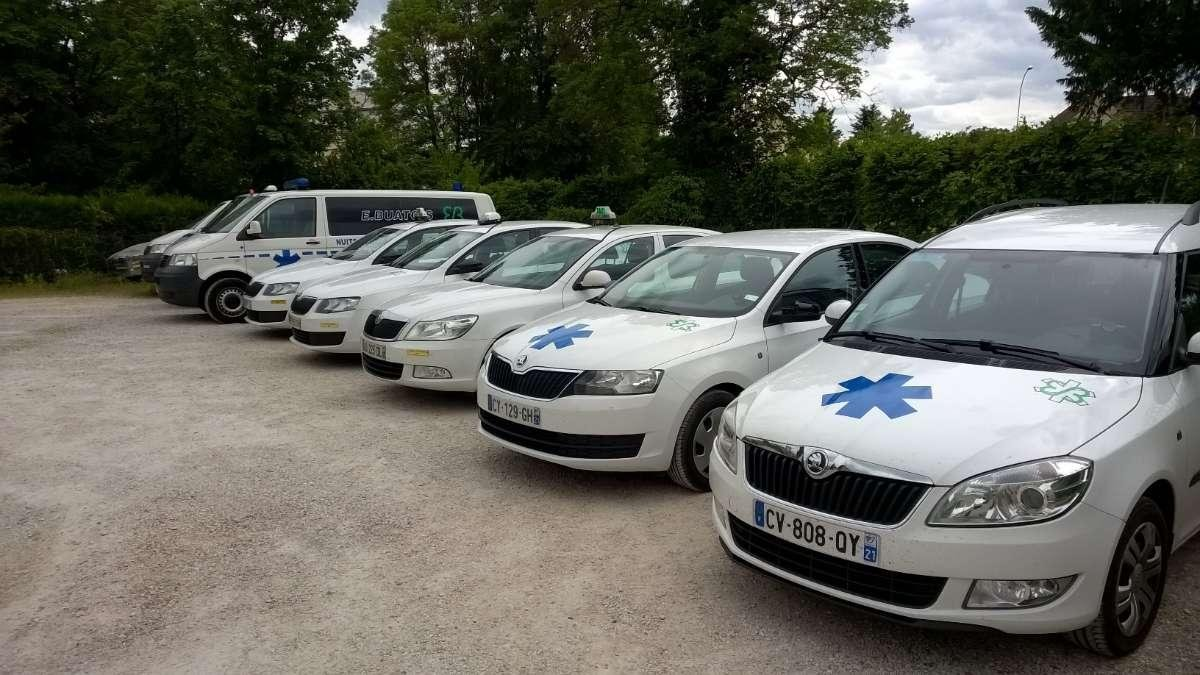 Une rangée de véhicules d'urgence blancs arborant des étoiles bleues est garée à l'extérieur.
