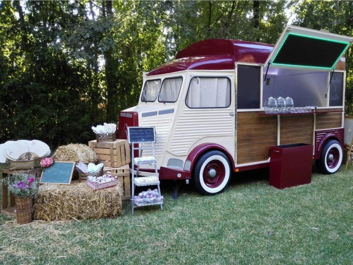 Camión de comida vintage con pintura roja y crema, instalado al aire libre sobre césped.
