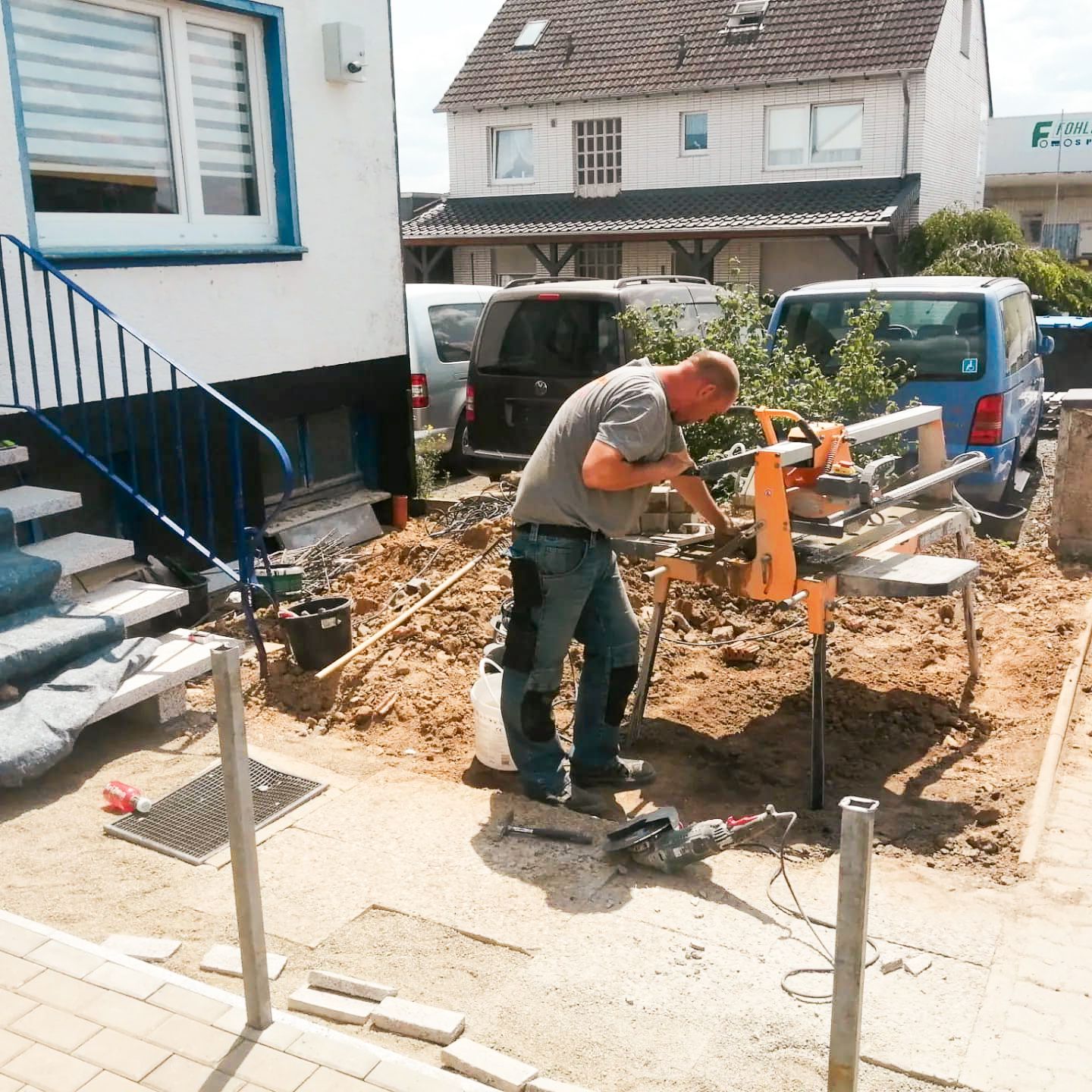Ein Mann arbeitet an einer Maschine vor einem Haus