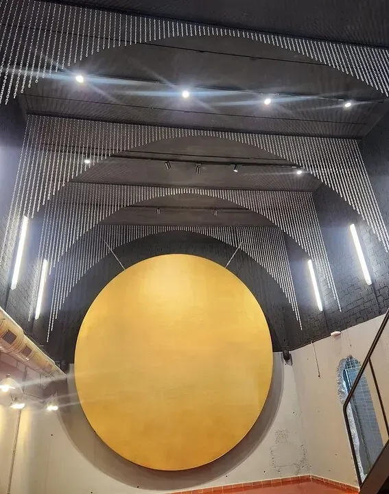 Un gran círculo amarillo cuelga del techo de un edificio.