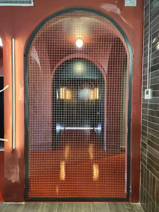 Una puerta con un patrón de cuadrícula está en una habitación con una pared roja.