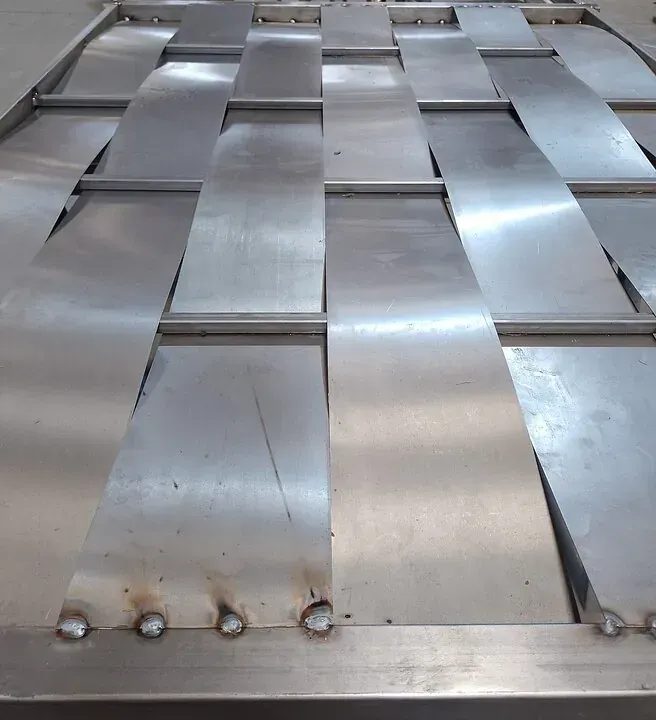 Un primer plano de una valla de acero inoxidable con agujeros.