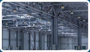 Un gran almacén con muchas vigas de metal y luces colgando del techo.