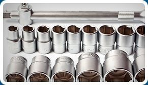 Un montón de enchufes y una llave inglesa están alineados sobre una mesa.