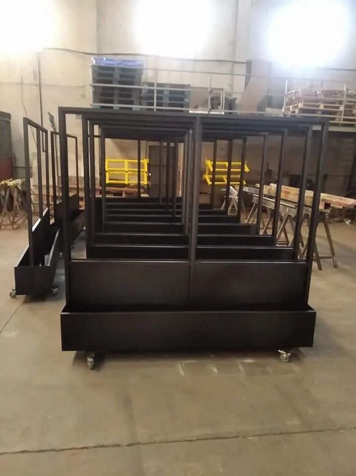 Una fila de cajas de metal negras con ruedas en un almacén.