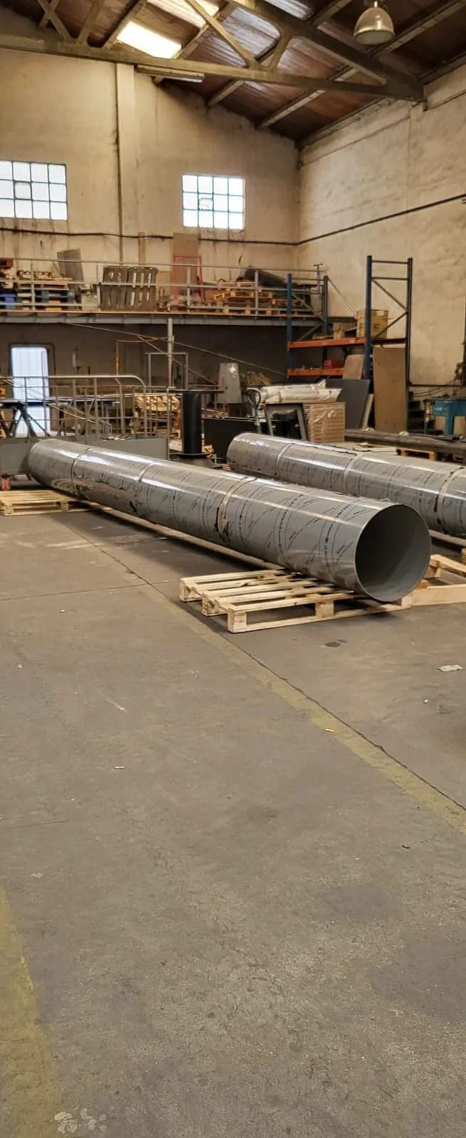 Un almacén lleno de muchos tubos de metal sobre paletas.