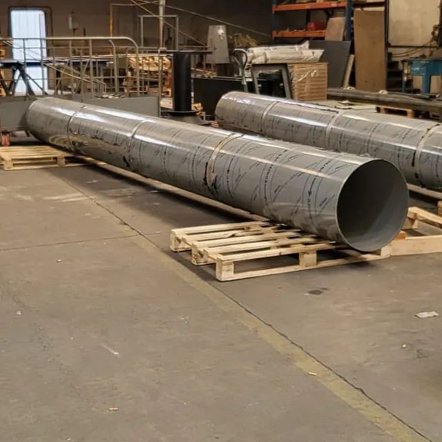 Un montón de tubos están apilados uno encima del otro sobre palés de madera.