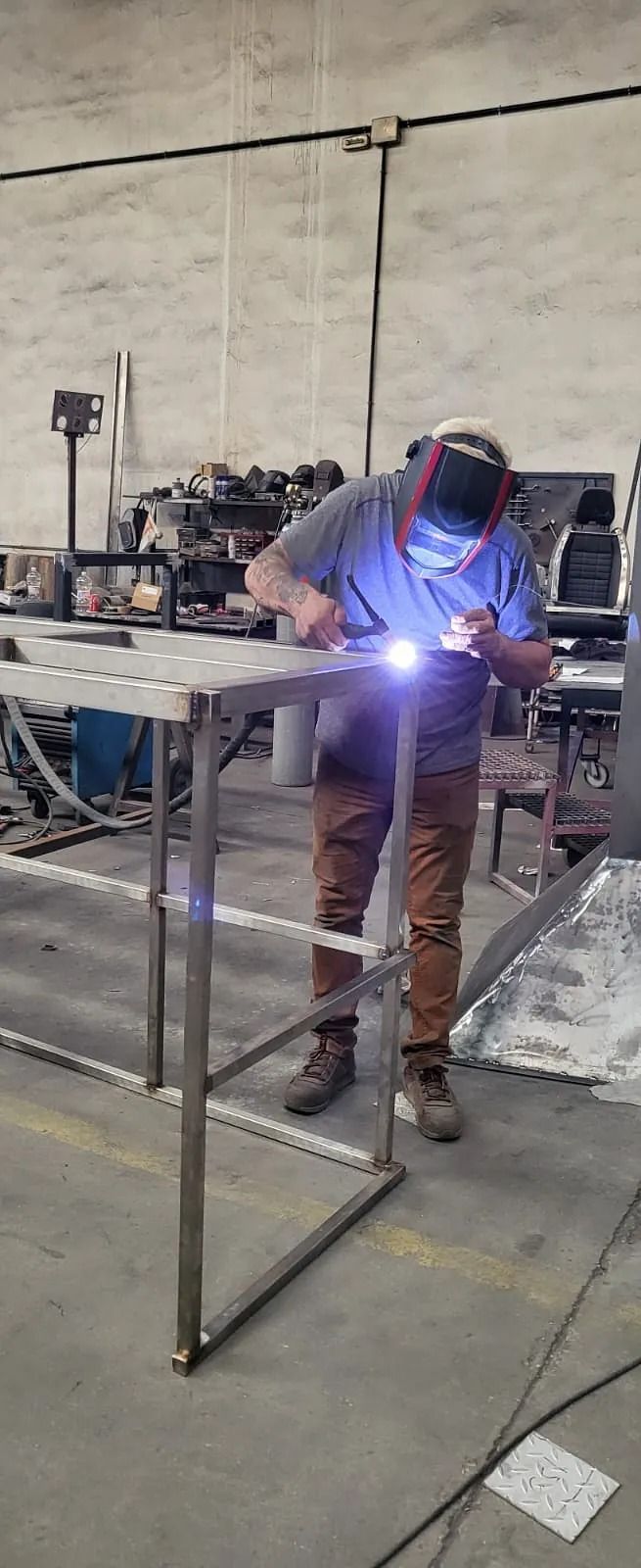 Un hombre está soldando una estructura metálica en una fábrica.
